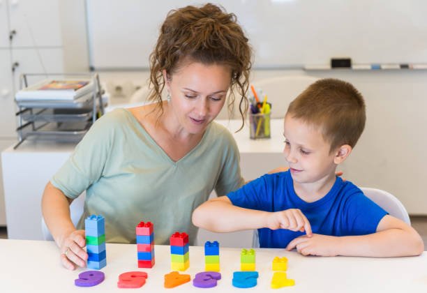 A boy having play-based speech therapy with a woman